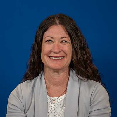 A white woman in her 40s with long, wavy brown hair.