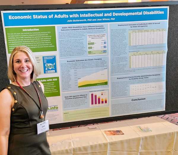 a white woman poses smiling by the poster she is presenting